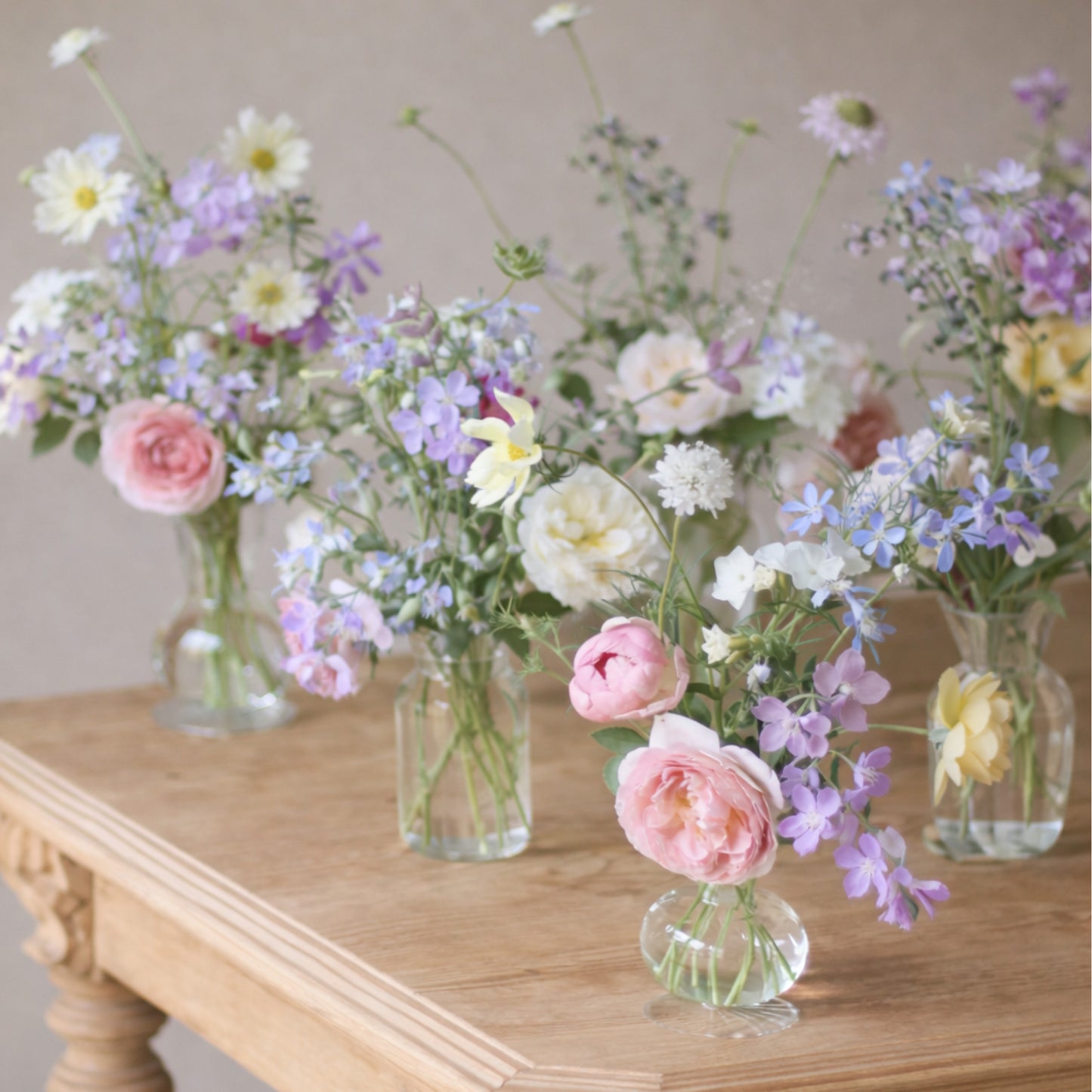 Pastel bud vase trio with blush, lavender, blue, cream, and white garden flowers.