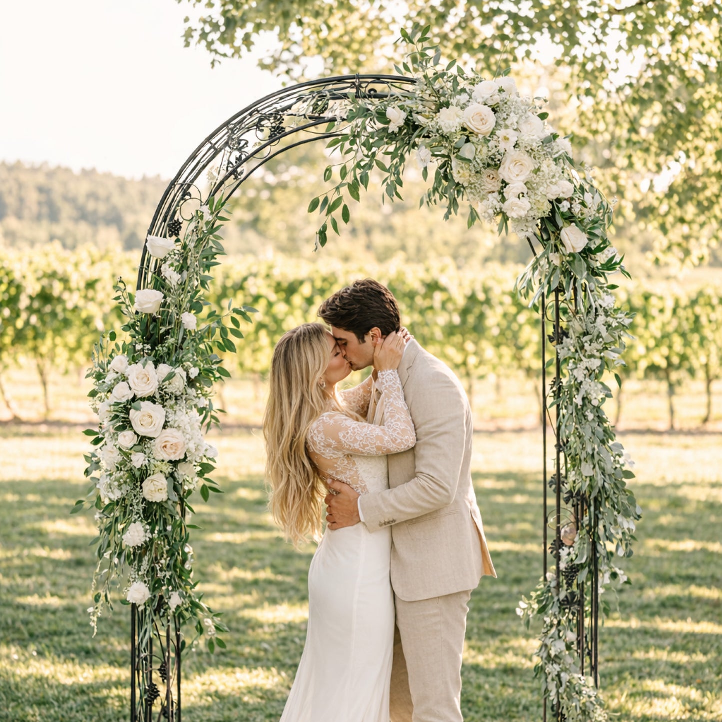 Porcelain ceremony arch floral swags in soft white blooms and trailing greenery styled asymmetrically on a romantic garden ceremony arch.