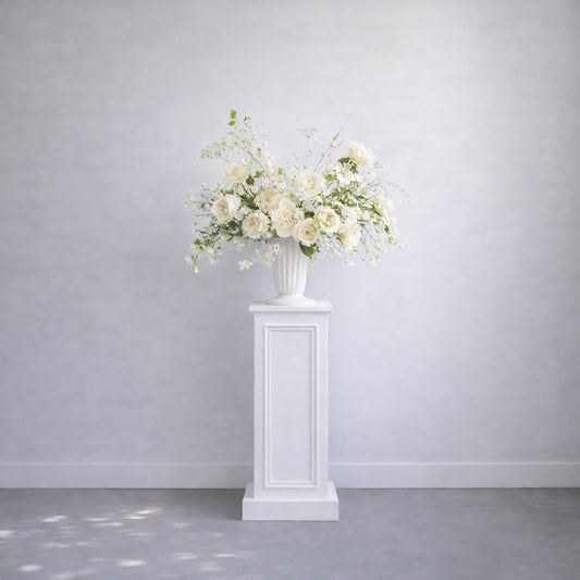 Porcelain Ceremony Urn Arrangement elevated on white pedestal featuring romantic white florals and airy garden-inspired ceremony styling.