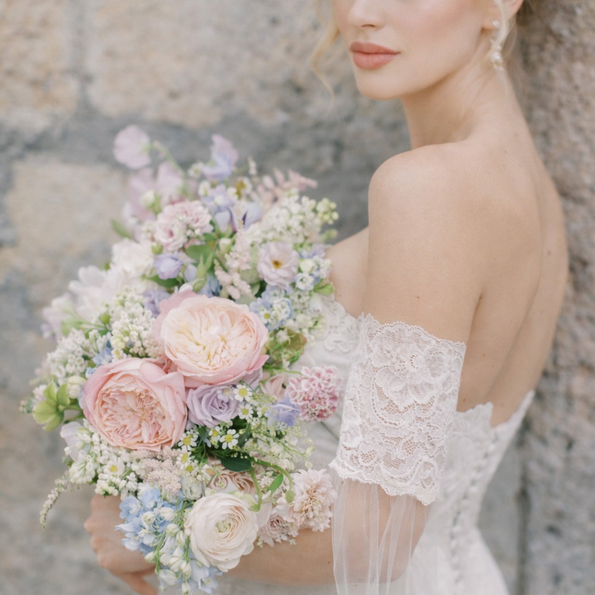 Bride holding pastel garden-style bridal bouquet with blush and lavender flowers.