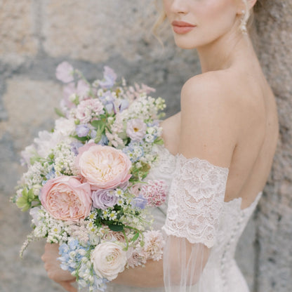 Bride holding pastel garden-style bridal bouquet with blush and lavender flowers.