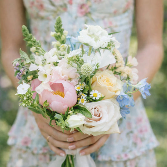 Close-up of pastel bridesmaid bouquet with blush, blue, cream, and white flowers.