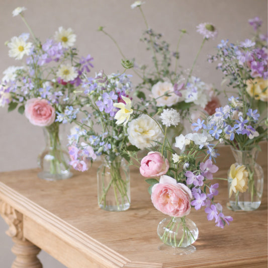 Pastel bud vase trio with blush, lavender, blue, cream, and white garden flowers.