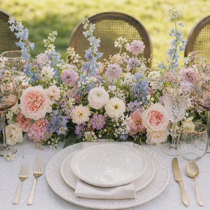 Pastel floral runner centerpiece with blush, lavender, blue, cream, and white garden flowers