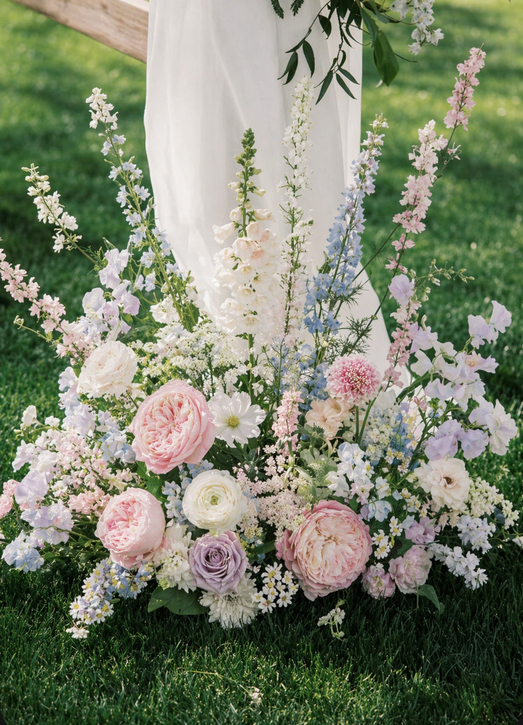Pastel ground meadow flowers framing romantic outdoor wedding ceremony.