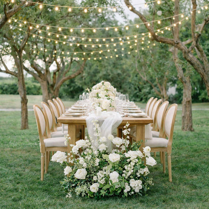 Porcelain Additional Ground Meadow Arrangement styled beside long outdoor banquet table with layered white blooms and romantic garden atmosphere.