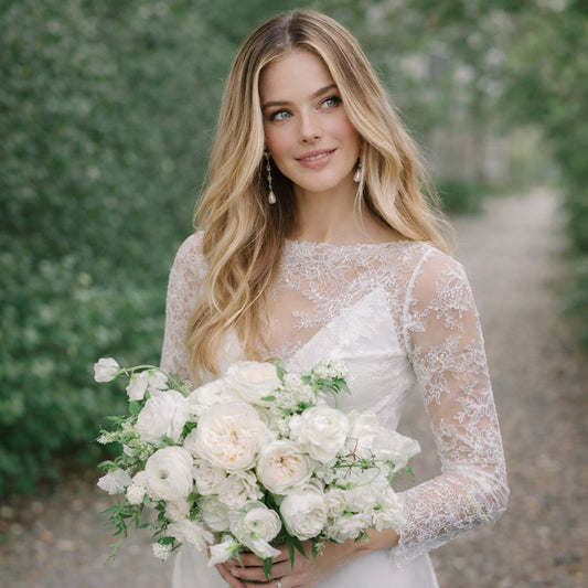 Bride holding the Porcelain bridal bouquet featuring soft white roses and delicate seasonal florals in an airy editorial style.