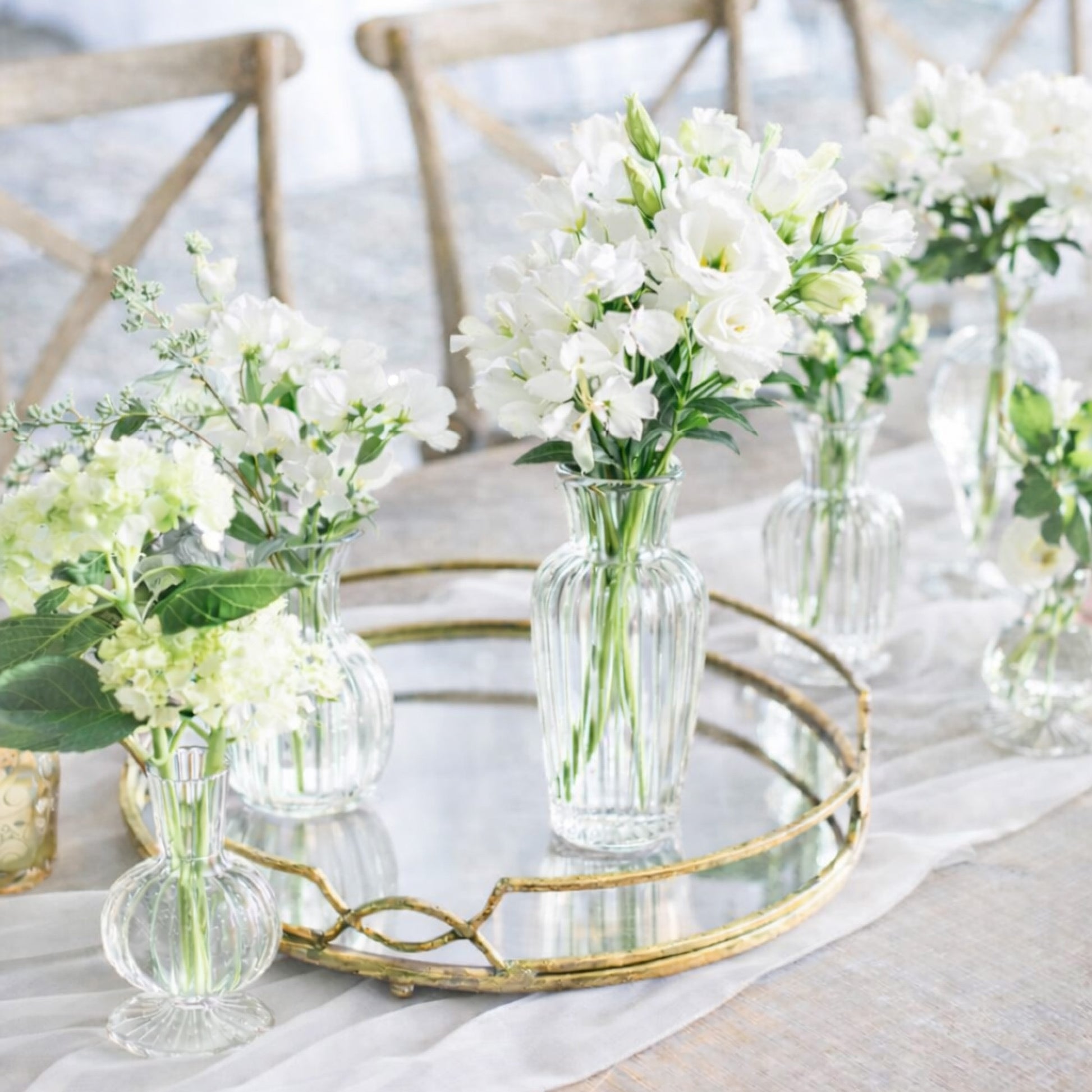 Porcelain Bud Vase Trio with delicate white seasonal blooms arranged in clear glass vases on romantic neutral reception table.