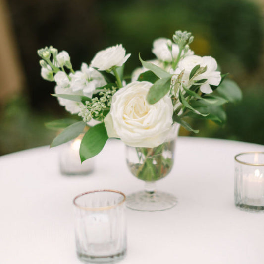 Porcelain Glass Compote Accent with white garden roses and airy seasonal blooms arranged in clear footed glass vase on reception table.