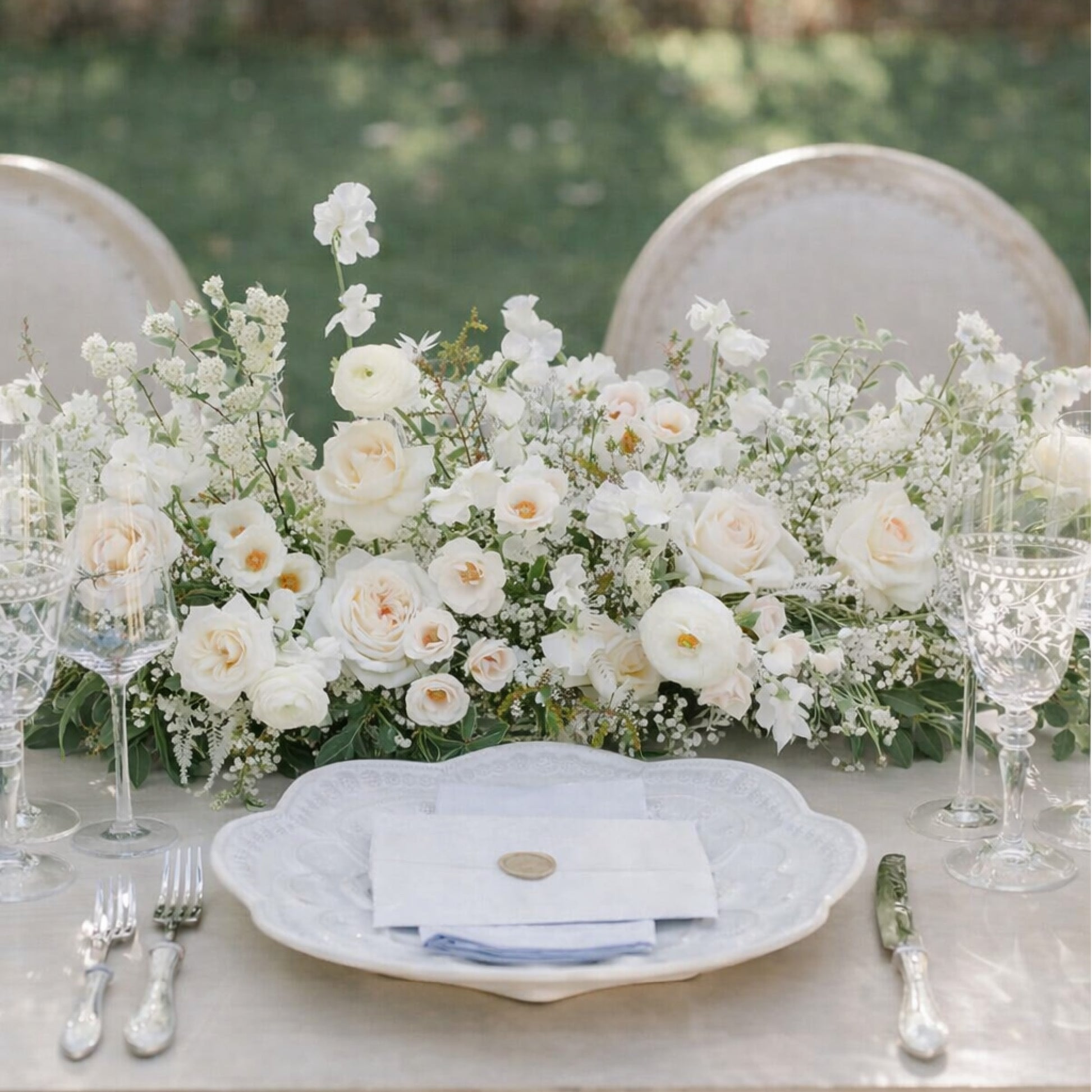 Porcelain Growing Garden Runner with layered white blooms and airy greenery styled across an elegant reception table setting.
