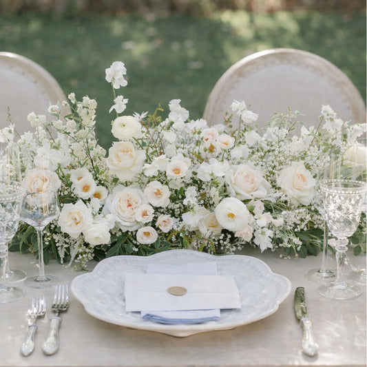 Porcelain Growing Garden Runner with layered white blooms and airy greenery styled across an elegant reception table setting.
