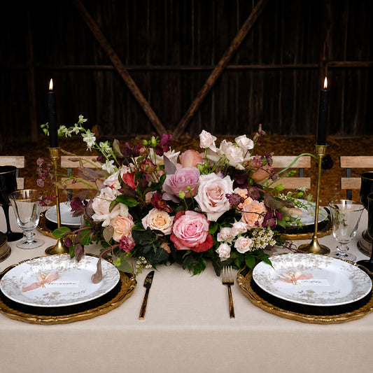 Moody meadow-style wedding centerpiece with burgundy, mauve, blush, and autumn florals