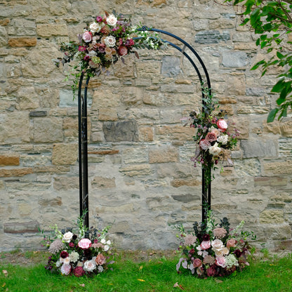 Moody floral swags styled on romantic outdoor wedding ceremony arch