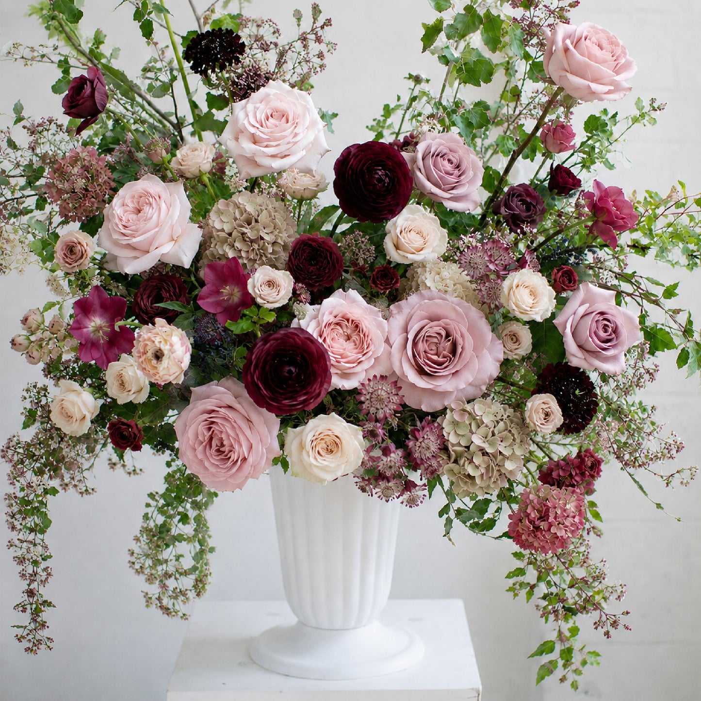 Detail of moody burgundy and mauve ceremony urn arrangement with garden roses and autumnal seasonal foliage.
