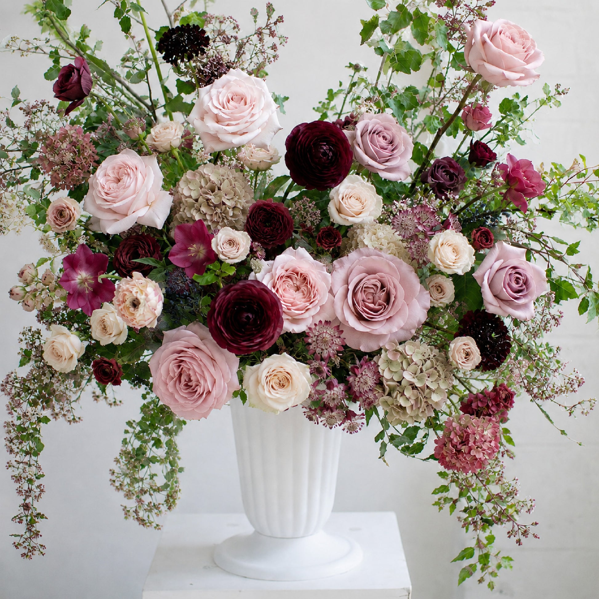 Detail of moody burgundy and mauve ceremony urn arrangement with garden roses and autumnal seasonal foliage.