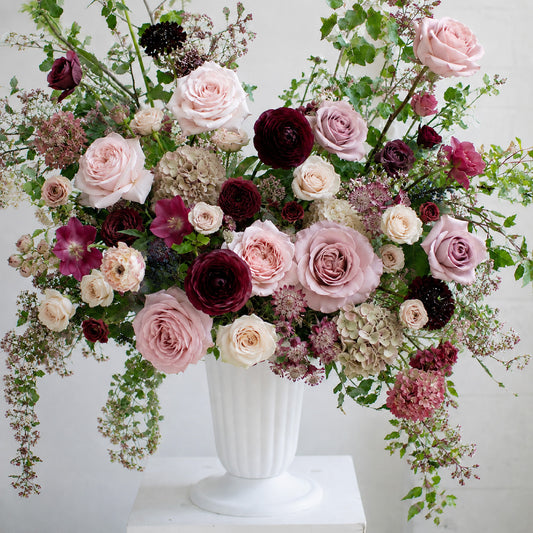 Detail of moody burgundy and mauve ceremony urn arrangement with garden roses and autumnal seasonal foliage.