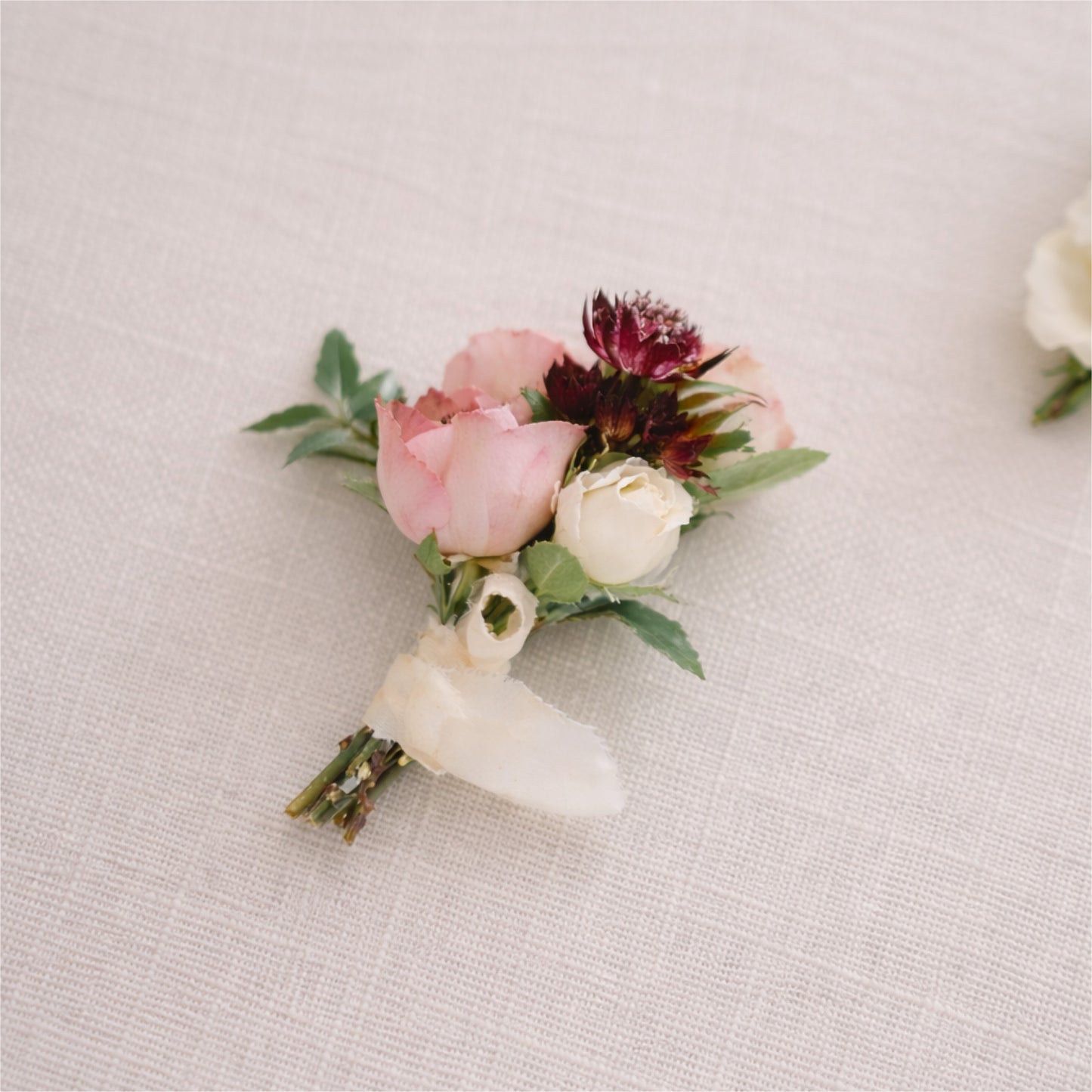 A moody boutonnière in burgundy, blush, and warm cream.