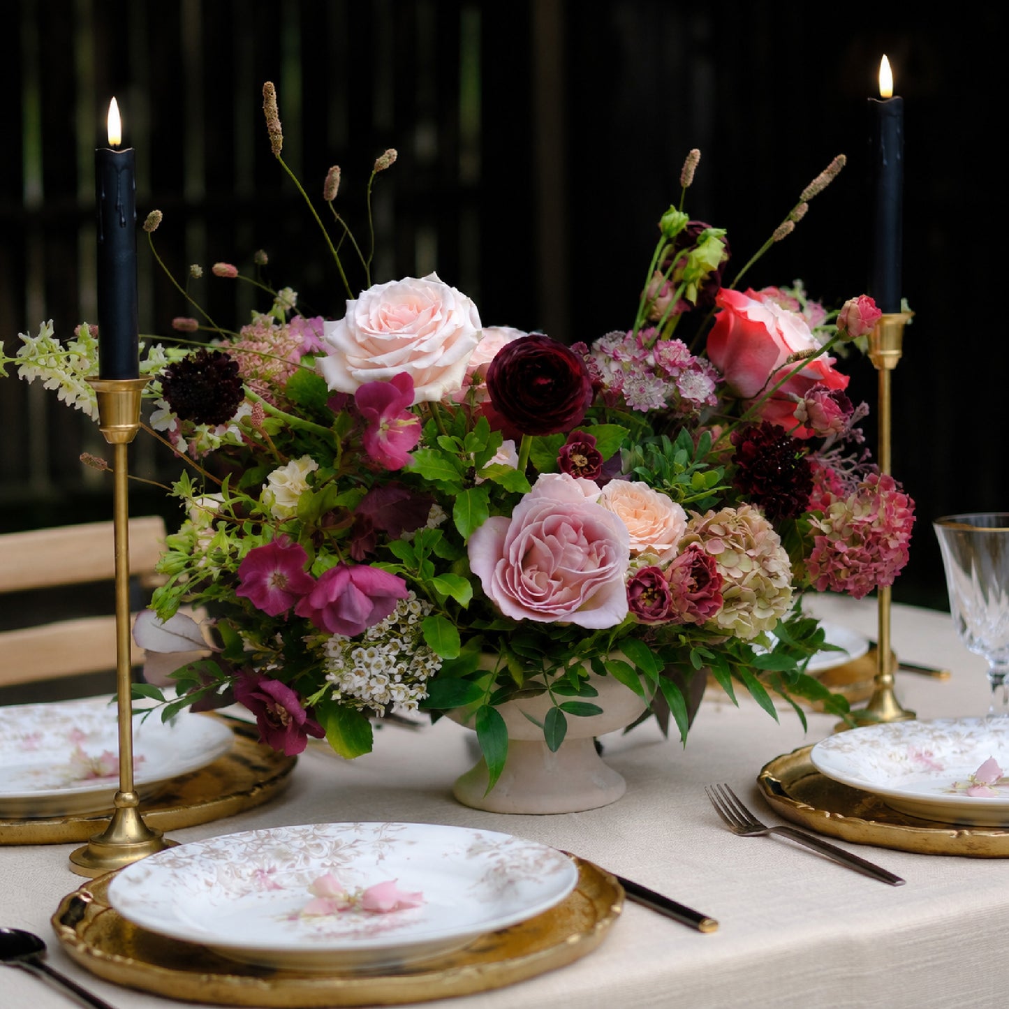 Side view of moody heirloom compote wedding centerpiece with burgundy and mauve seasonal florals