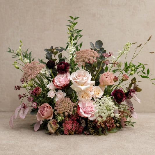 Moody burgundy, blush & mauve ceremony meadow arrangement with garden roses and autumnal seasonal foliage.