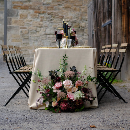 Moody burgundy and blush ground meadow flowers styled beside romantic wedding sweetheart table