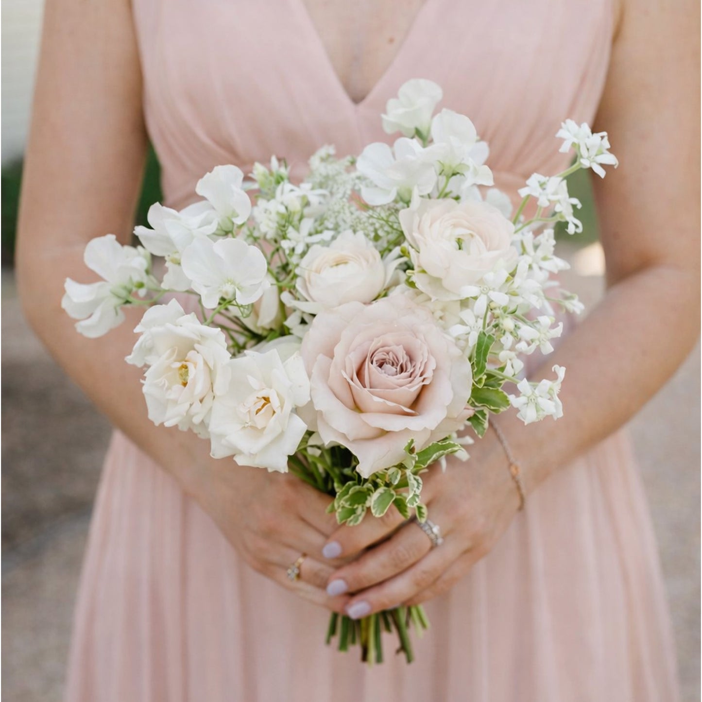 Rosewater bridesmaid bouquet with blush garden roses and airy ivory seasonal blooms held by bridesmaid in soft pink dress.