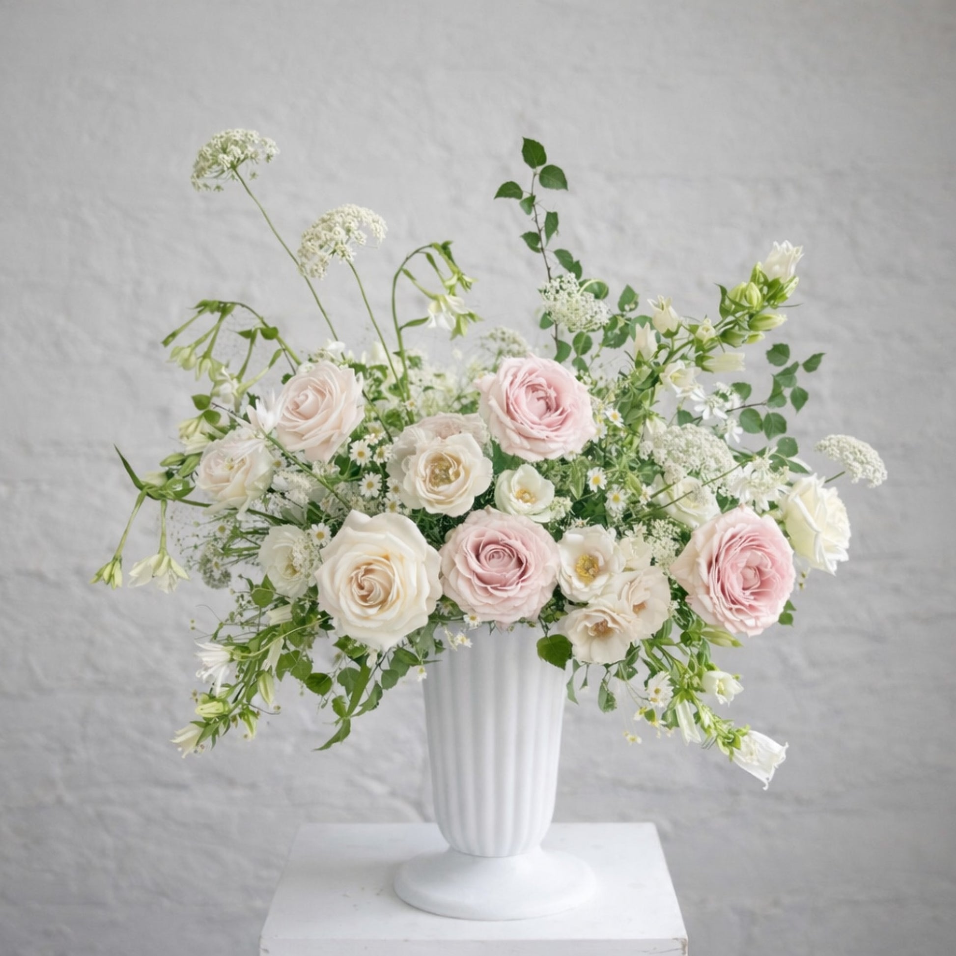 Rosewater ceremony urn arrangement with blush and ivory garden blooms in a classical white urn.