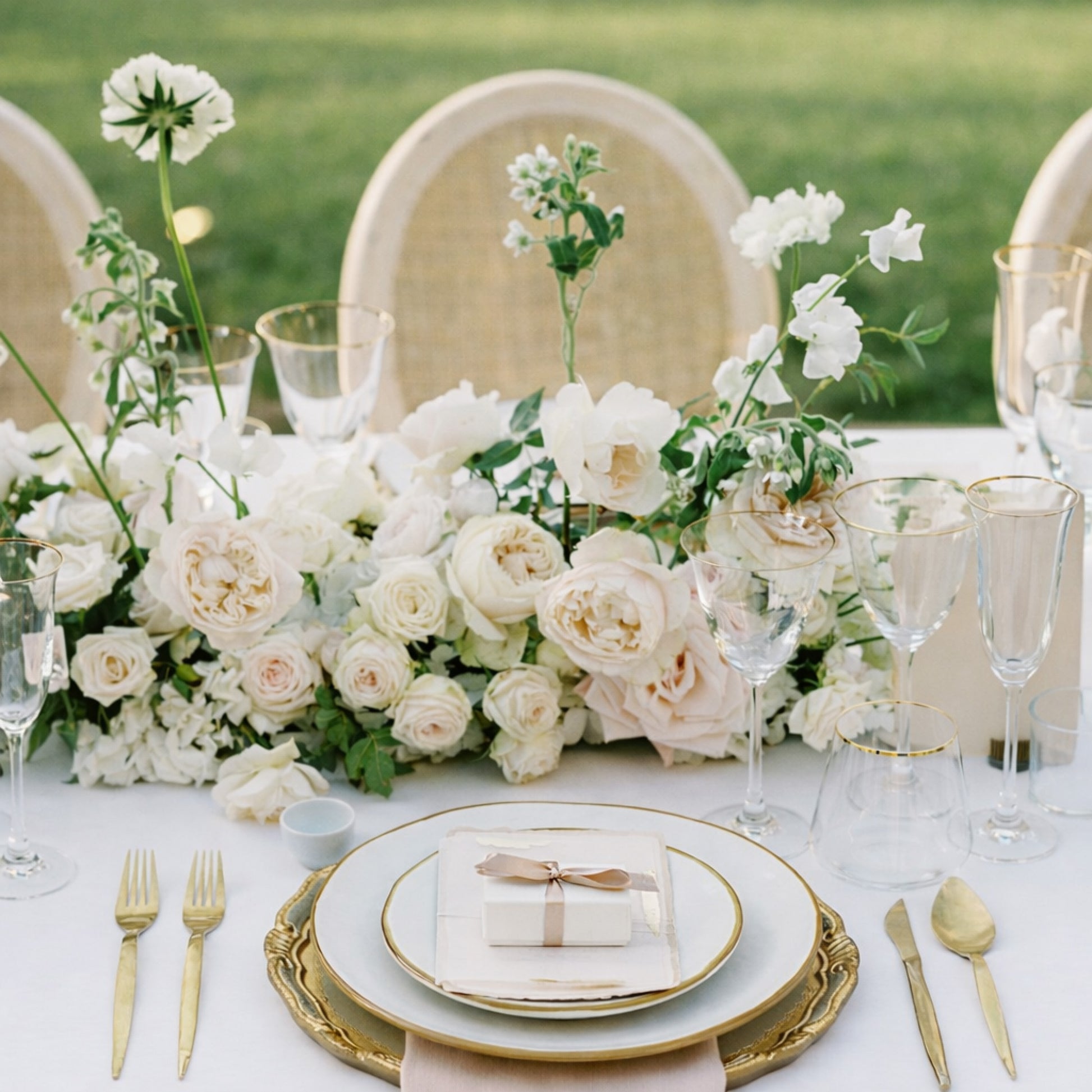 Rosewater growing garden runner with blush and ivory florals styled low across an elegant reception table.
