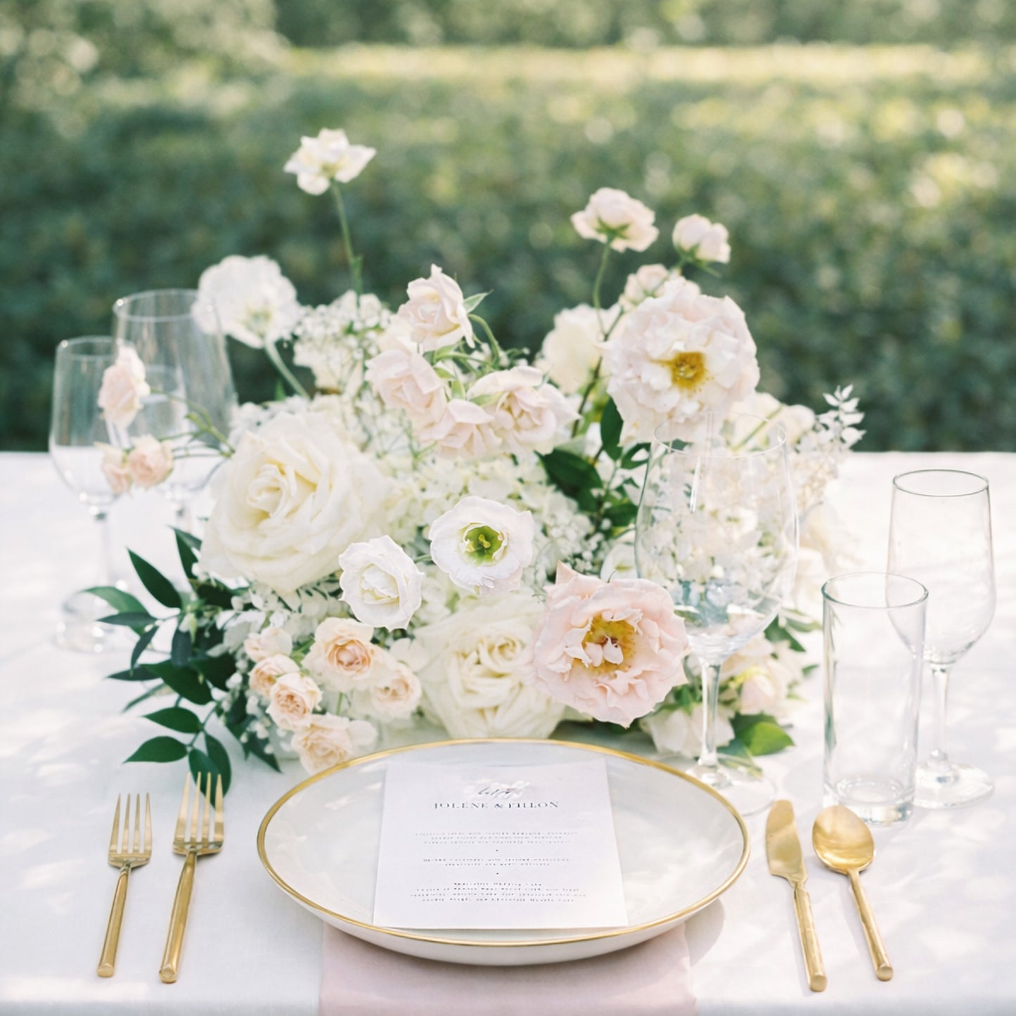 Rosewater meadow composition centerpiece with blush and ivory garden blooms styled on an elegant outdoor reception table.