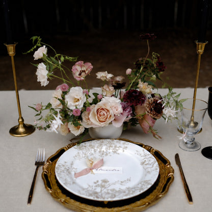 Moody still-life wedding centerpiece with burgundy, blush, and ivory seasonal flowers