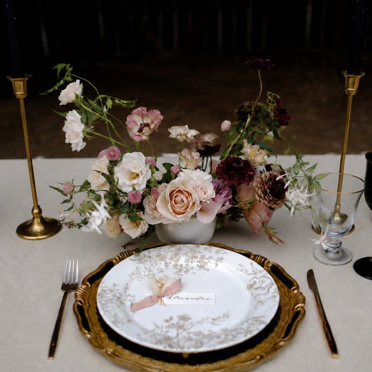 Moody still-life wedding centerpiece with burgundy, blush, and ivory seasonal flowers