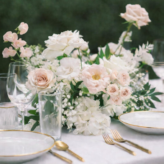 Rosewater meadow composition centerpiece with airy blush and ivory florals arranged on a romantic reception tablescape.